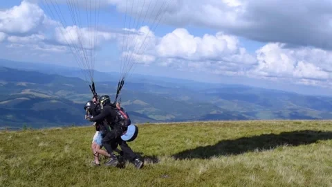 Mens help a paragliding instructor take off in tandem with a young guy. Stock Footage 258946409