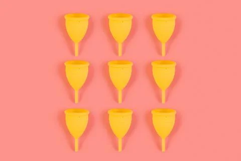Menstrual yellow cups pattern on a pink background. Monochrome zero waste con Stock Photos