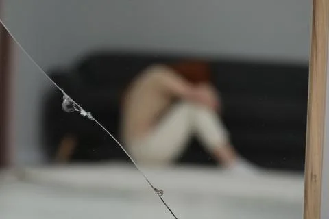 Mental problems. Blurred reflection of depressed woman in broken mirror Stock Photos