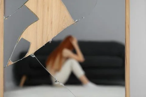 Mental problems. Blurred reflection of depressed woman in broken mirror Stock Photos