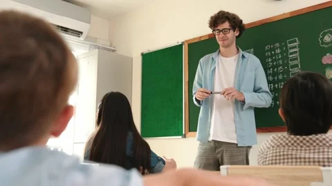 Mentor looking around classroom while standing in front of blackboard. Pedagogy. Stock Footage 271148115