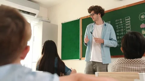 Mentor looking around classroom while standing in front of blackboard. Pedagogy. Stock Footage 277958218