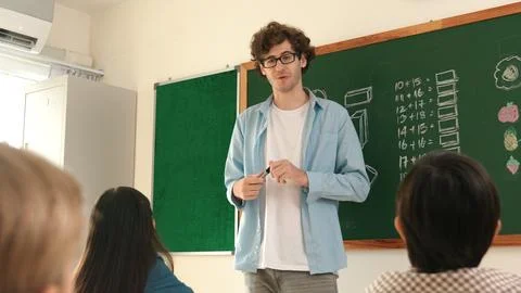 Mentor looking around classroom while standing in front of blackboard. Pedagogy. 스톡 사진