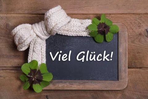 Menu board with good luck message in german - clovers and white bow on wooden Stock Photos