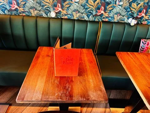 Menu on wooden table at a cozy Paris Le Saint Placide cafe with green banqu.. Stock Photos