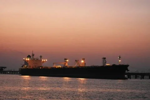 Merchant ship is offloading in the evening Foto stock