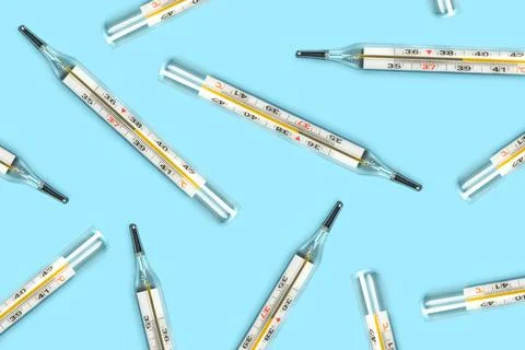 Mercury-in-glass thermometer creative pattern on blue background flat lay Stock Photos