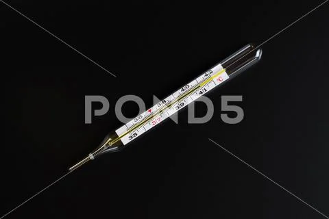 Mercury thermometer and pills on a black background. Stock Photos