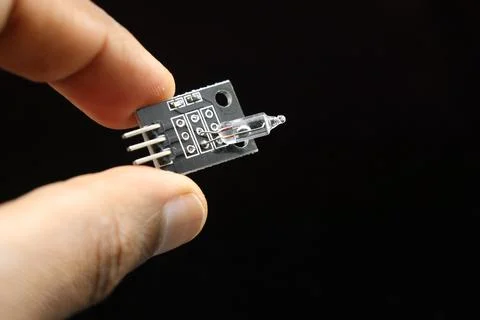 Mercury tilt switch sensor module held in hand isolated on black background 写真素材