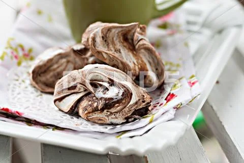 Meringue cake with chocolate lying a heap on a plate near cup Stock Photos