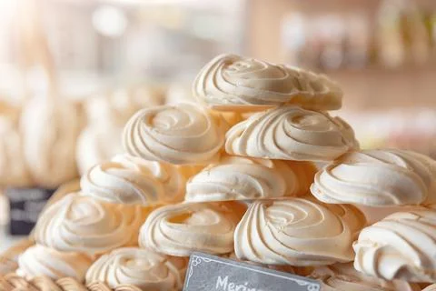 Meringue dessert stack delicate swirls displayed bakery warm light highlighting 스톡 사진
