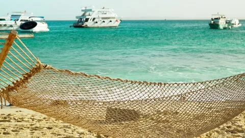 A mesh hammock on a sandy beach with a beautiful view of the sea bay. Video stock 323960457