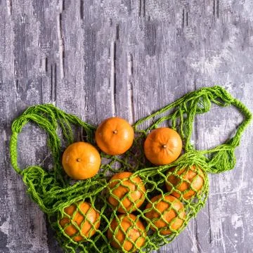 Mesh string bag with fresh oranges from supermarket on gray. .Top view Stock Photos