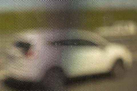 Mesh structure on glass of bus. Surface details of small holes. Blurry backgr Foto stock
