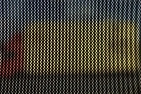Mesh structure on glass of bus. Surface details of small holes. Blurry backgr Foto stock