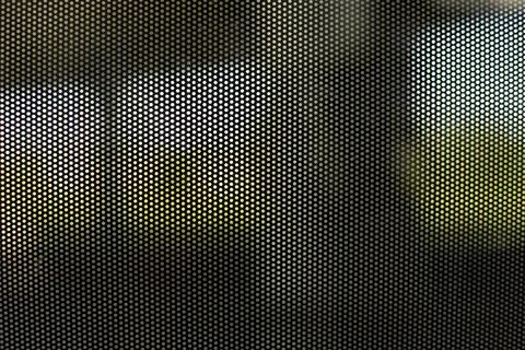 Mesh structure on glass of bus. Surface details of small holes. Blurry backgr Foto stock