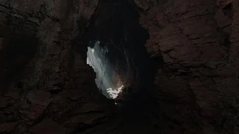 A mesmerizing cave with a ray of sunlight streaming through a small opening 스톡 일러스트