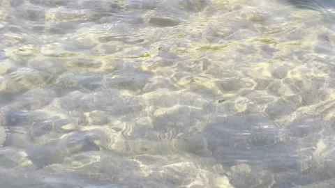 A mesmerizing close-up shot of crystal-clear water rippling over a shallow Stock-Footage 332539948