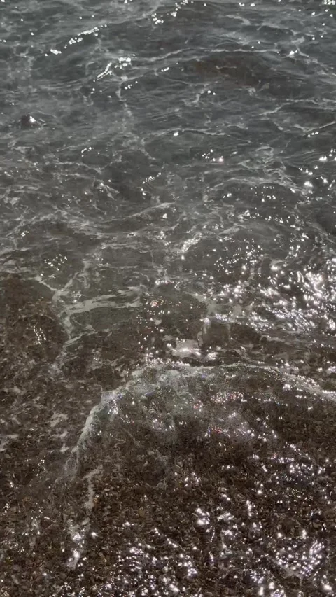 A mesmerizing close-up view of a sea wave rolling onto a sandy shore, capturi Stock Footage 301847351