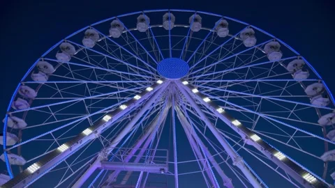 A mesmerizing ferris wheel adorned with vibrant blue and white lights rotat.. 库存影片 339213827