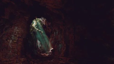 A mesmerizing green light shining through the entrance of a mystical cave 스톡 일러스트