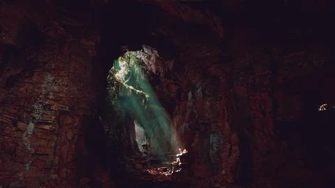 A mesmerizing green light shining through the entrance of a mystical cave 스톡 일러스트