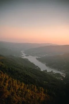 A mesmerizing landscape with a river flowing between forested mountains at dusk Stock-Fotos
