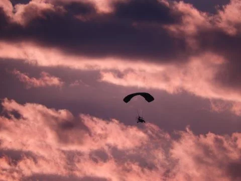 Mesmerizing scene of Paragliding in the dramatic sunset sky with clouds Stock Photos