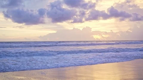 Mesmerizing sea waves ripple gently toward the sandy shore under a golden e.. Stock Footage 313381133