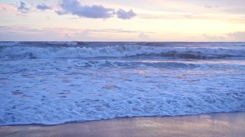 Mesmerizing sea waves ripple gently toward the sandy shore under a golden e.. Stock Footage 313381137