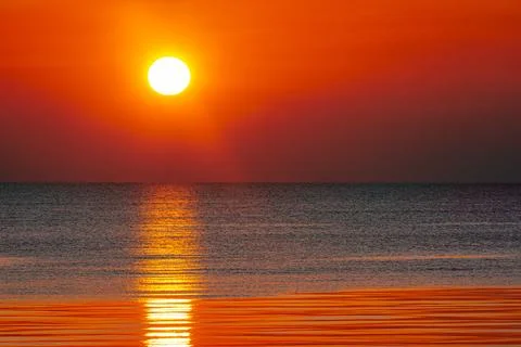 A mesmerizing sunset over the ocean, casting golden and orange hues Stock Photos