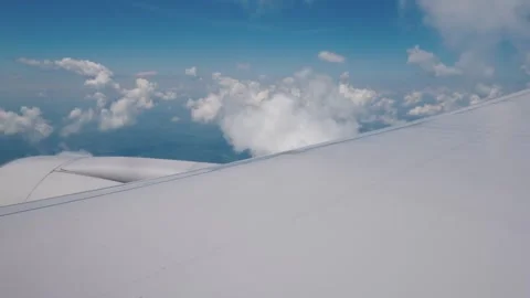 A mesmerizing view of fluffy white clouds and blue sky from airplane window.. Stock Footage 334790783