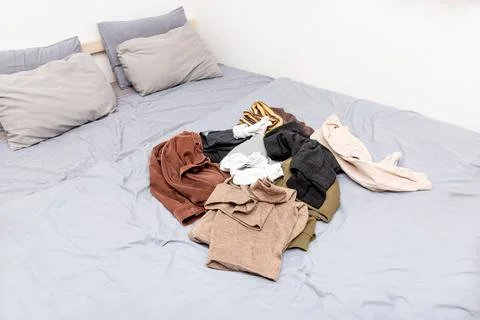 Mess pile of clothes on bed, sorting cloth in closet and making special place Stockfoto's