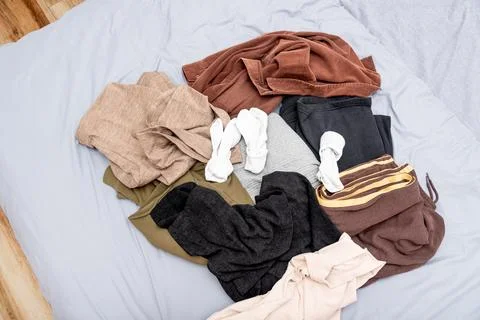 Mess pile of clothes on bed, sorting cloth in closet and making special place Stockfoto's