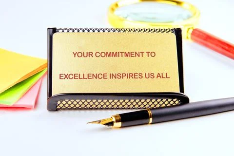 A message about commitment to excellence sits on a desk alongside colorful st Stock Photos