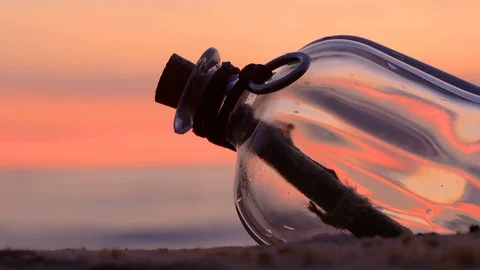 Message in the bottle against the Sun setting down Stock Footage 124427480