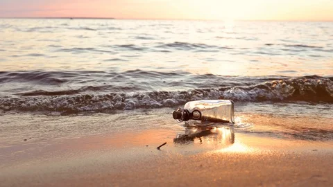Message in the bottle against the Sun setting down Stock Footage 129893093