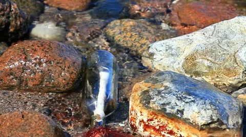 Message in a bottle is between rocks and water at the beach on the Baltic coast Stock Footage 11134610