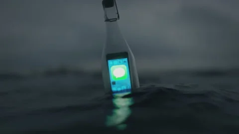Message in a bottle. A bottle floating in the sea with a smartphone inside Stock Footage 225331953