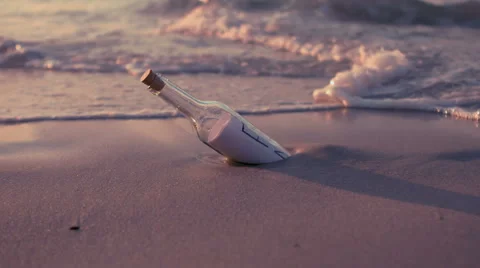 Message in a bottle covered by waves on the beach Stock Footage