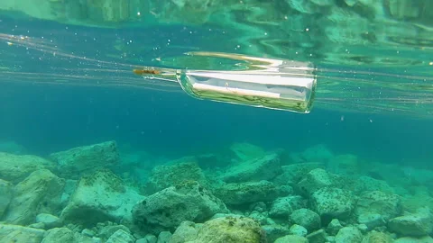 Message in a bottle. A message in a bottle floats on the surface of the sea Stock Footage 165499660