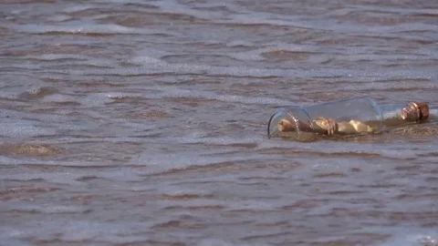 Message in bottle rolling on the sand, vacation on beach Stock Footage