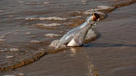A message in a bottle washed up on the beach by waves Stock Photos