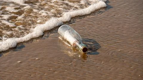 A message in a bottle washed up on the beach by waves Stock Photos