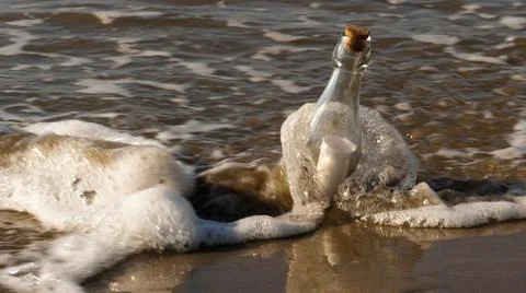 A message in a bottle washed up on the beach by waves Stock Photos