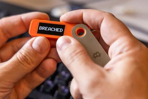 Message Breached on screen of hardware Bitcoin wallet in a hands Stock Photos