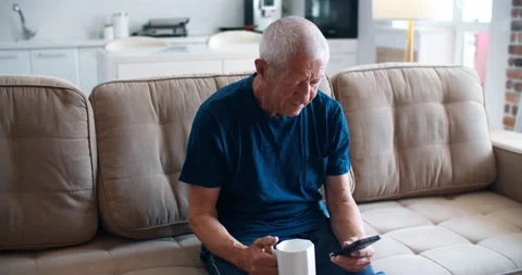 Message for children. An elderly man sits on the couch and writes a message on a Stock Footage 136552387