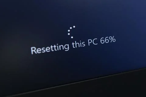 The message on the computer screen "Resetting this PC 66% " Stock Photos