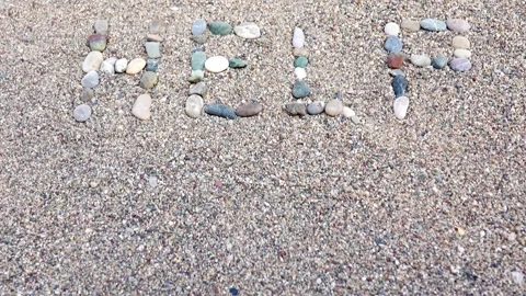 A message of help, from the pebbles spread out on the sandy shore of the beach Stock Footage 284002696