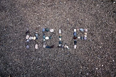 A message of help, from the pebbles spread out on the sandy shore of the beac Stock Photos
